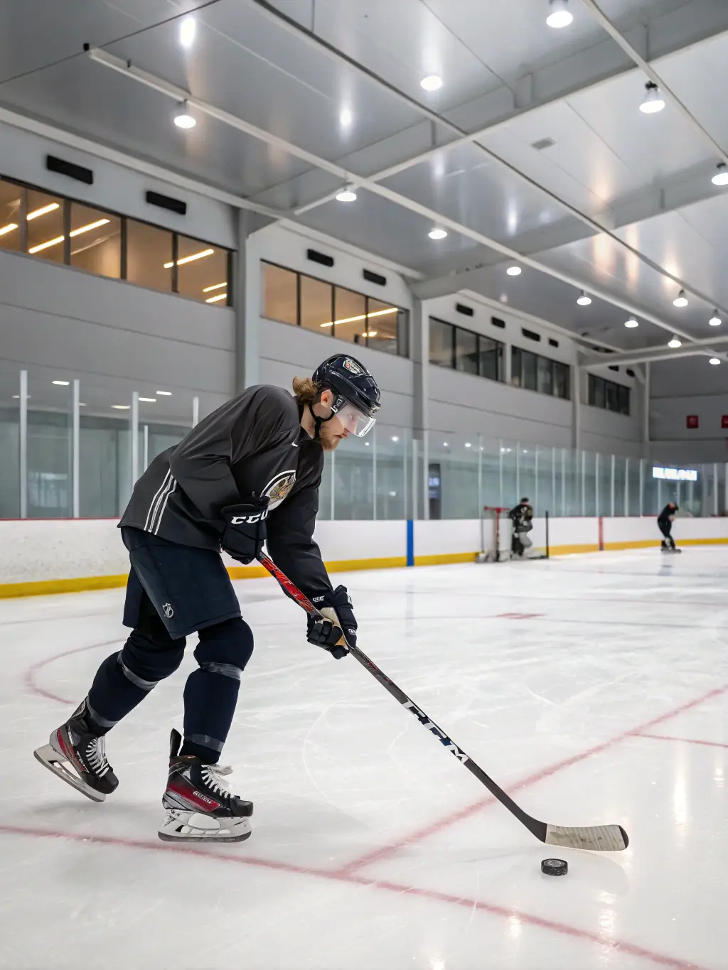 A young hockey player in full gear, intensely focused, practicing their skating technique on the ice at IceSportdPhuket, with Coach Michael observing closely.